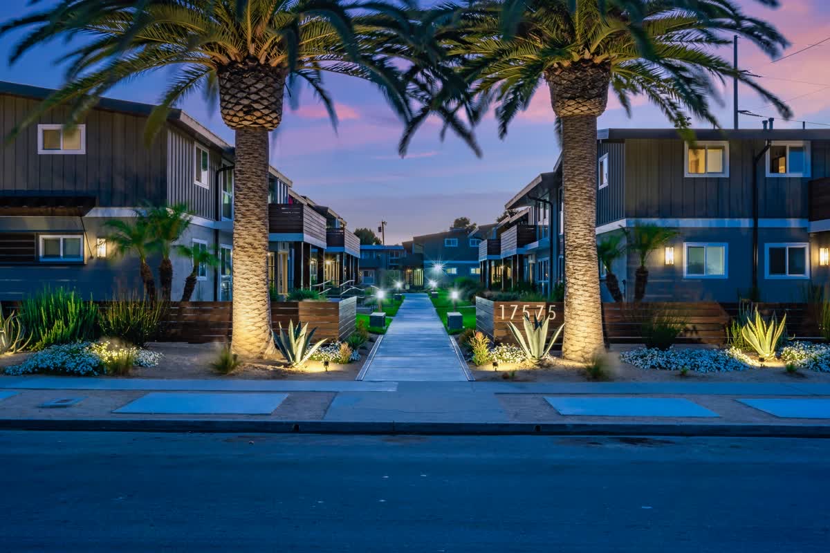 Palm lined illuminated entrance to Palm View Village Torrance at dusk